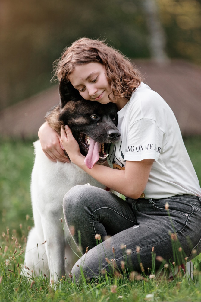 Dog and owner kneeling down and hugging at the end of a training session outside